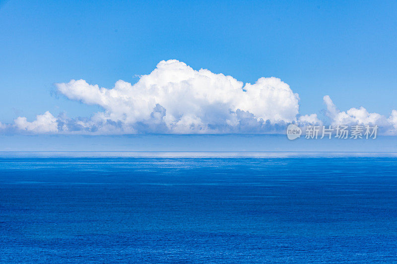 白云漂浮在湛蓝的天空，在平静的大海之上