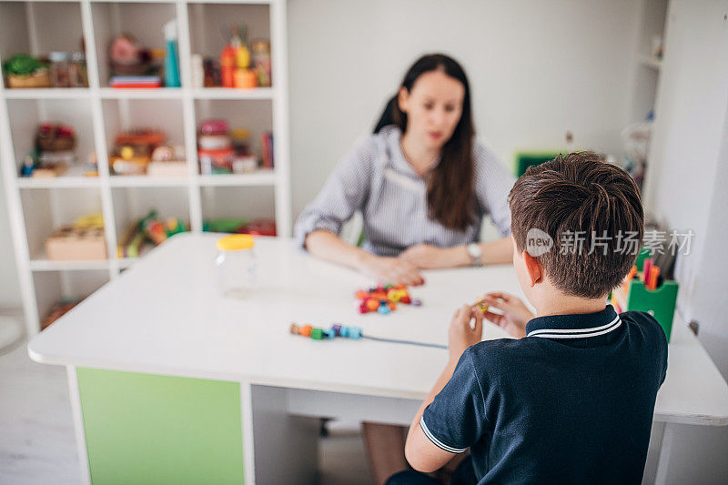 一个男生和他的职业治疗师一起做项链