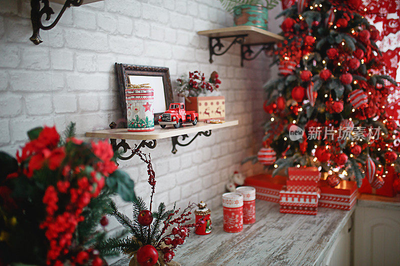 在白色的客厅里，红色和白色装饰的圣诞树下，礼物装在盒子里。新的一年,
