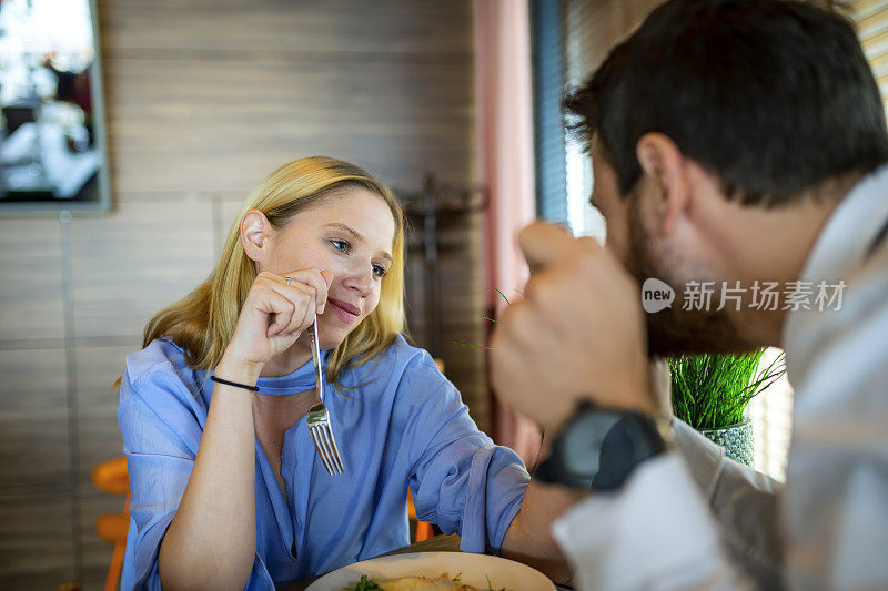 一对漂亮的商人夫妇正坐在餐厅里吃着美味的饭菜。