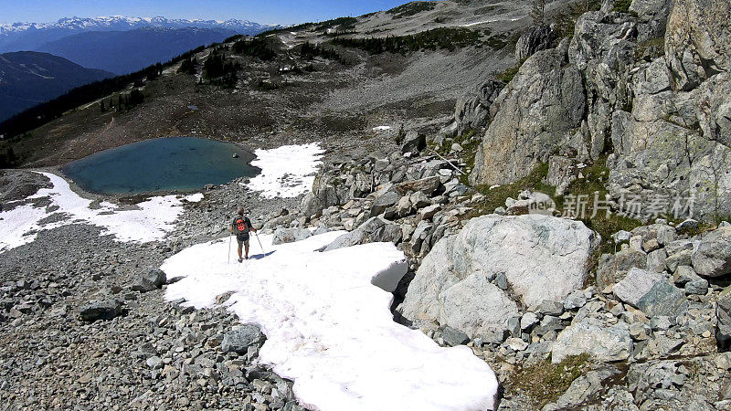 徒步旅行者沿着积雪的山坡跑下去