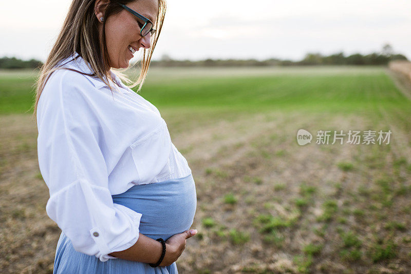 孕妇抱着她的肚子在户外