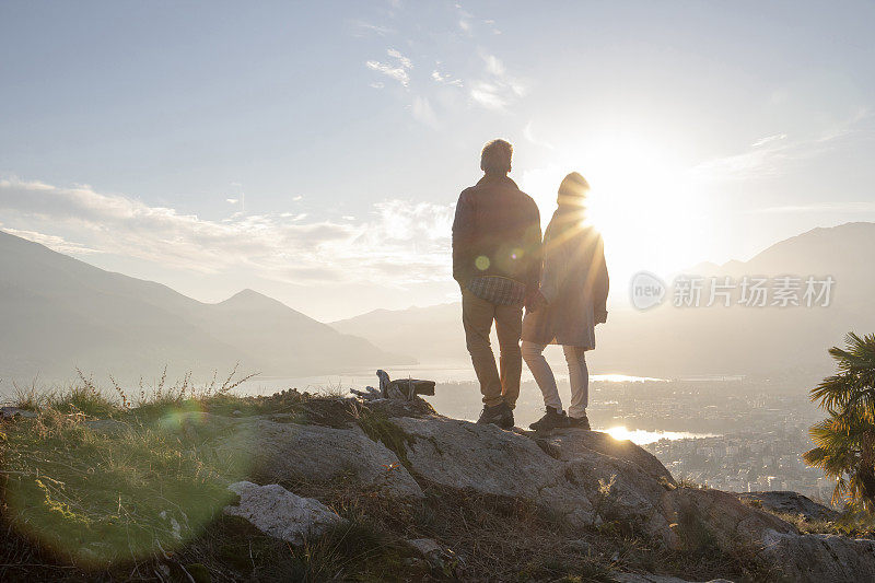 成熟的夫妇沿着阳光明媚的山脊，夕阳西下