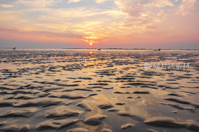 在平静的海面上，夏日日落时沙滩上的涟漪