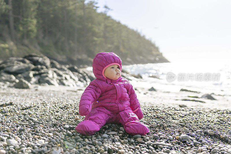 美丽的一岁小女孩独自坐在户外的海滩岩石上