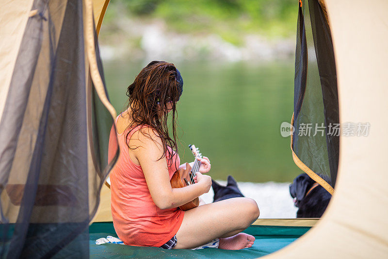 一个女人和狗在帐篷里玩尤克里里琴