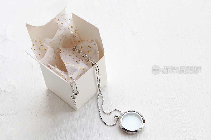 白色背景上的银色项链。豪华银珠宝与玻璃附近的礼品盒。给她的小礼物。漂亮珍贵的女人珠宝，还有复印空间