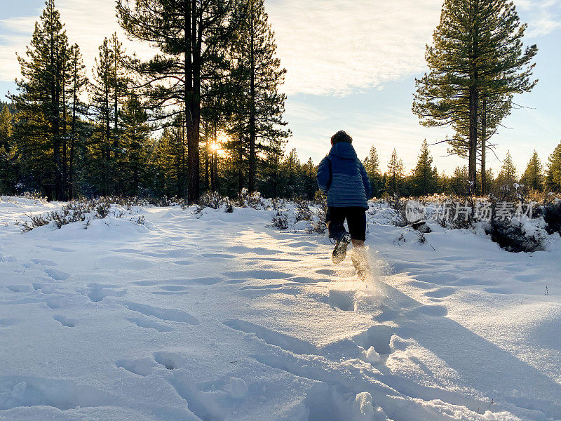 日落时分，孩子们在白雪覆盖的森林里奔跑玩耍