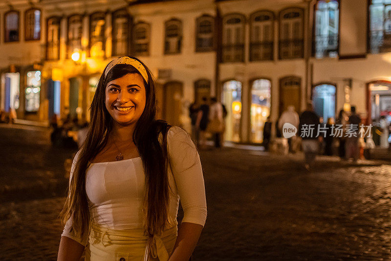 在这个历史悠久的城市里，一名女游客微笑着享受夜晚。