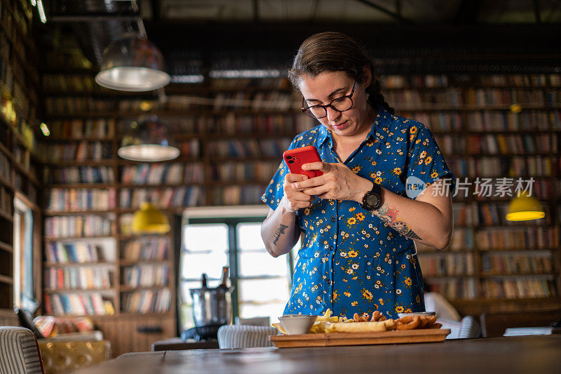 一名女子在餐厅里用手机、拍照、分享食物