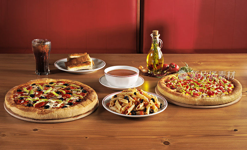 餐厅餐桌上有披萨，意大利面，汤和苏打水