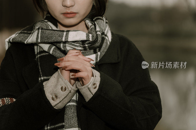 一个亚洲女孩在阴天用围巾搓手