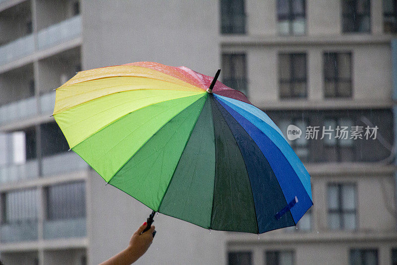 雨点落在彩虹伞上，天以自然为背景