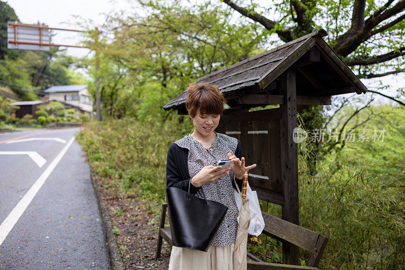 在旅游地点用智能手机等车的日本妇女