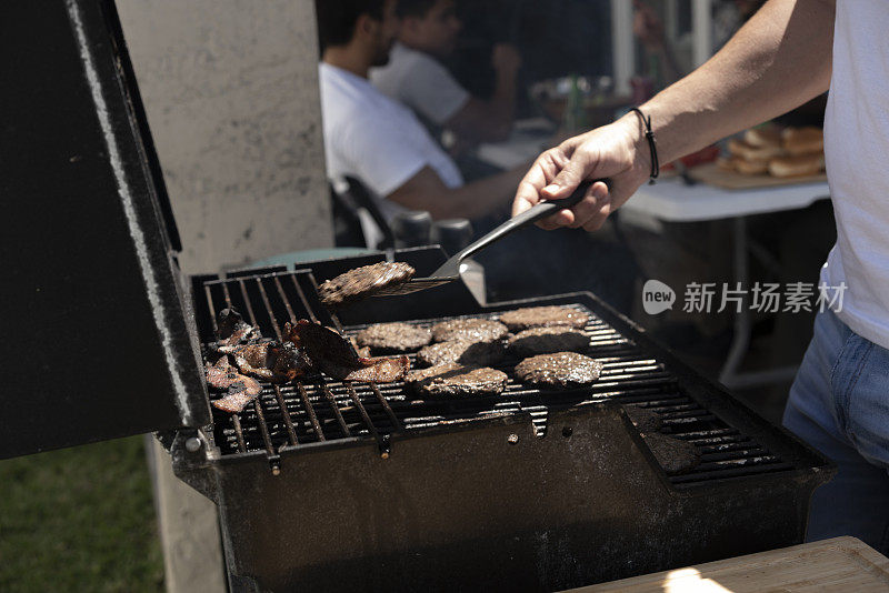 快乐的年轻人在烧烤会上和朋友一起烤汉堡