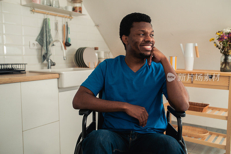 一个年轻的非洲裔美国人坐在轮椅上微笑的画像在他的房子里享受