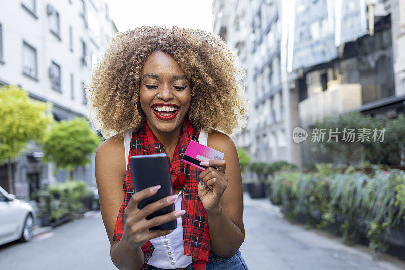 开朗的女子通过信用卡和智能手机在线支付