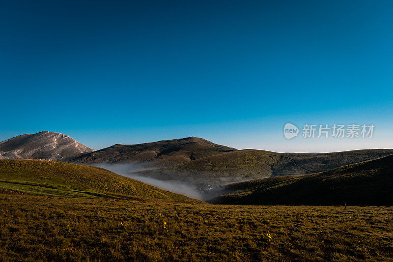 绿色的草地，雾蒙蒙的低地，山脉景观