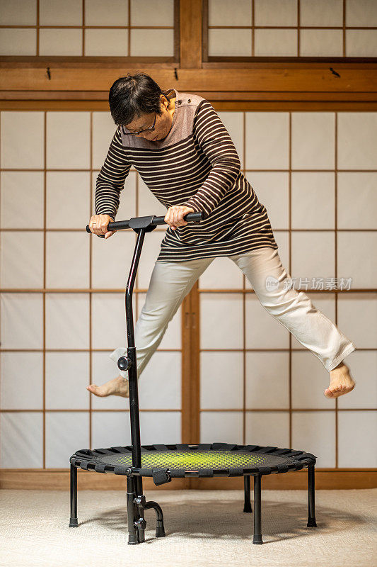 一名日本老年妇女在家里蹦床上跳