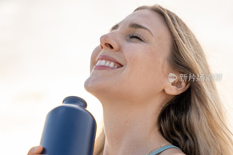 年轻女子用可重复使用的瓶子喝水的肖像