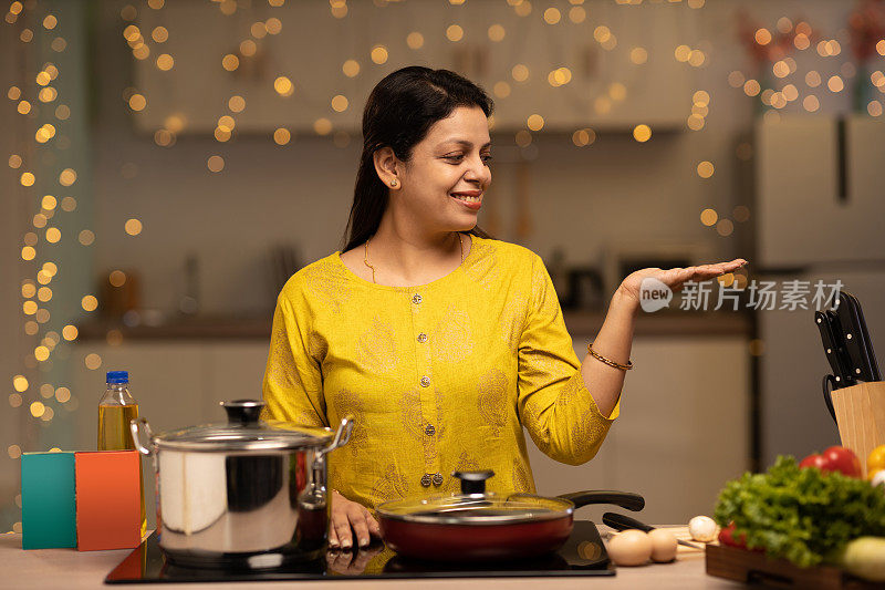 印度妇女在厨房做饭时享受的画像。库存图片