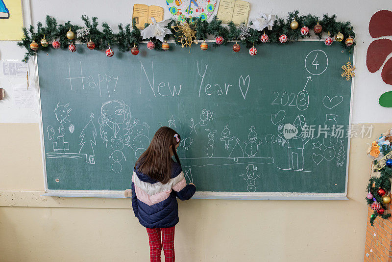 小学女生在黑板上画画，装饰教室迎接新年