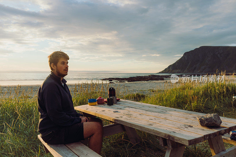 一名男子在风景优美的海滩露营，日落时分在罗福特群岛野餐