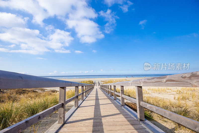 德国下萨克森州东弗里西亚，冬季的Norddeich，沙丘上通往北海的木桥与蓝天