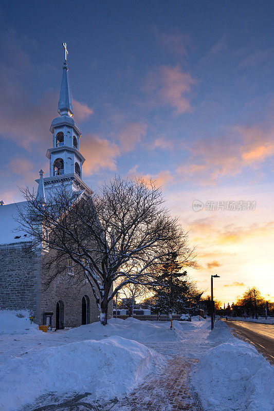 在冬天下雪的路上，教堂后面的晚霞