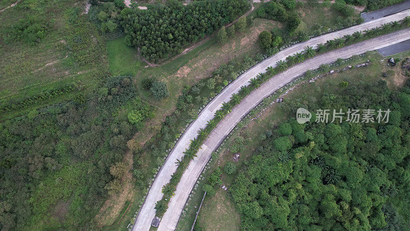 水泥路横跨一片绿地，室外自然风光，航拍无人机俯瞰混凝土路横跨森林。