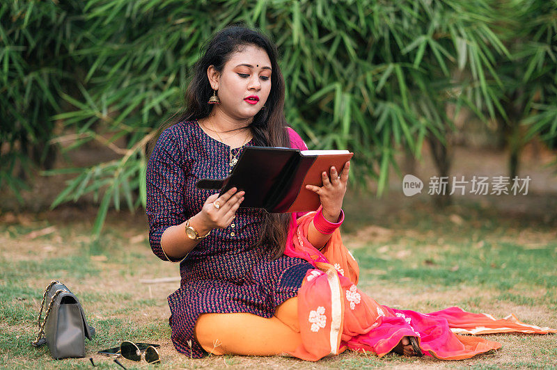 年轻的印度女大学生在公园看书