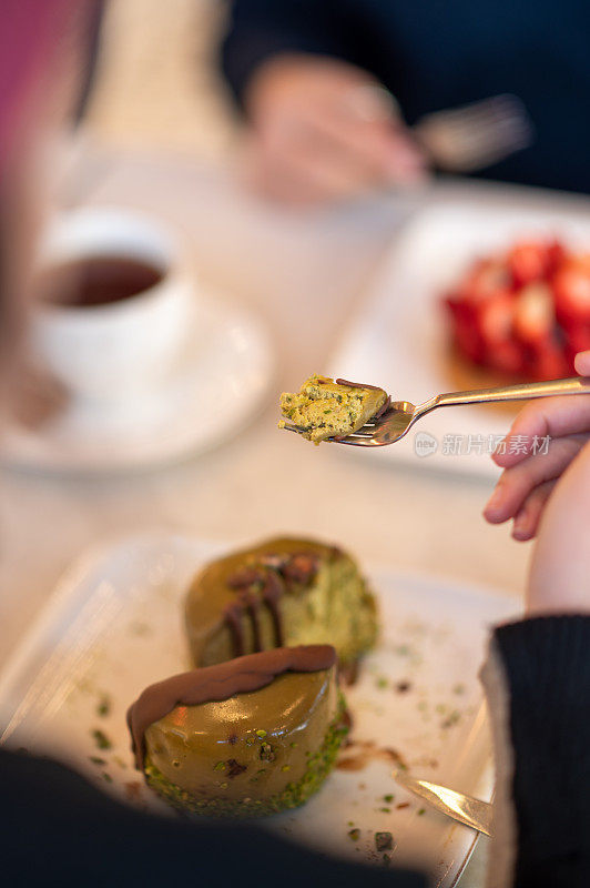 一个女人和她的朋友在café吃巧克力蛋糕的特写镜头