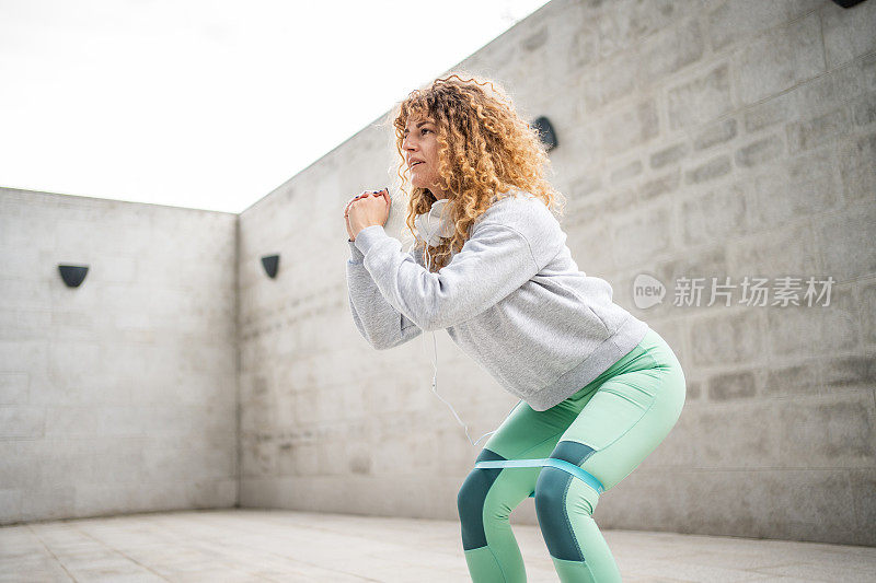 年轻活力的女运动员在水泥墙外训练，照顾健康的生活和身心的力量，用阻力轮胎锻炼