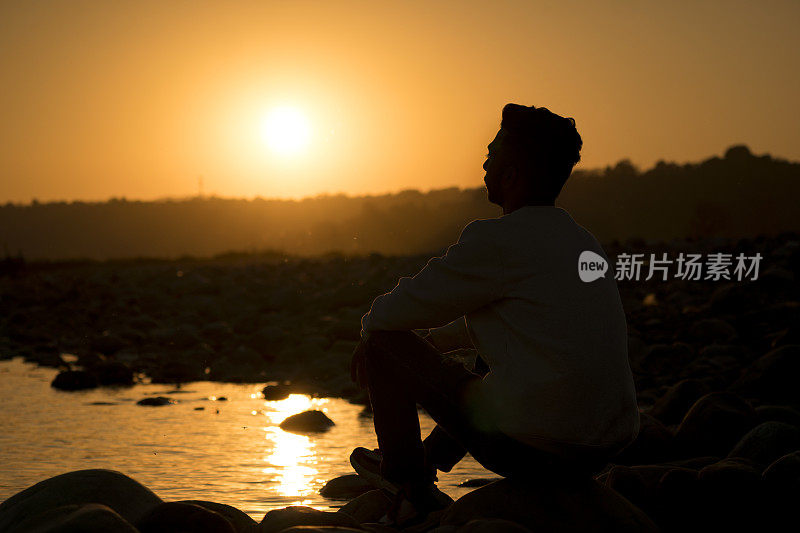 一个年轻人看日落的剪影。
