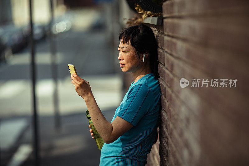 一名年轻的日本女子在健身后使用智能手机休息