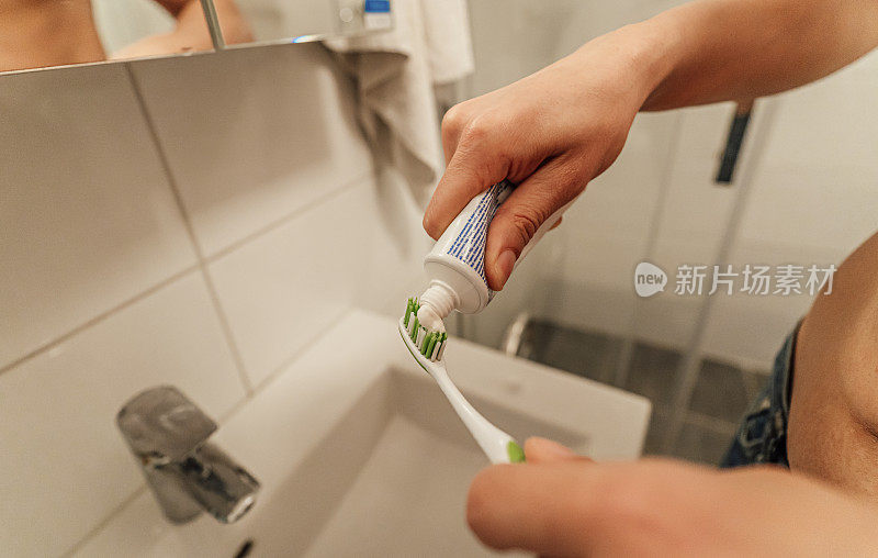 男性的手把牙膏挤在牙刷上