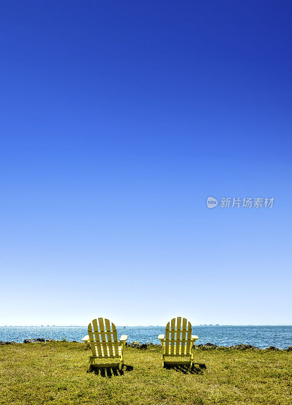 海边绿色景观上的两把户外空木椅