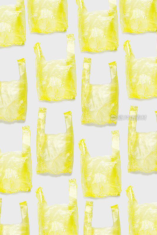 最小趋势图案黄色塑料袋在浅色背景，可生物降解的包装废物，一次性袋杂货或垃圾，无袋日。聚乙烯包。无塑料概念