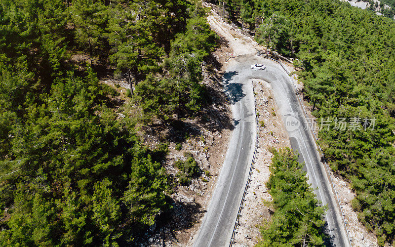 在森林山区的道路上行驶的车辆用无人机拍摄沥青弯道