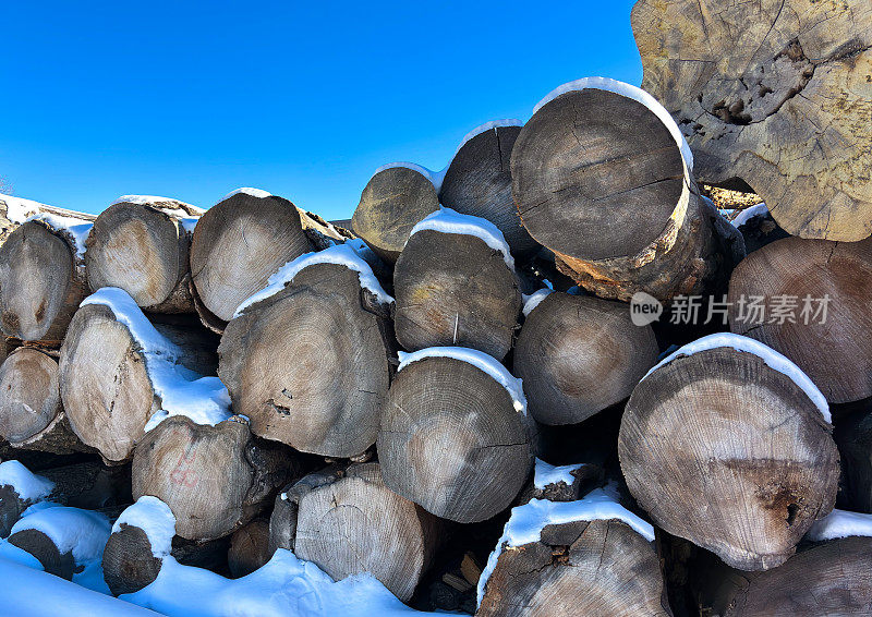 堆着雪的原木，充满活力的蓝天