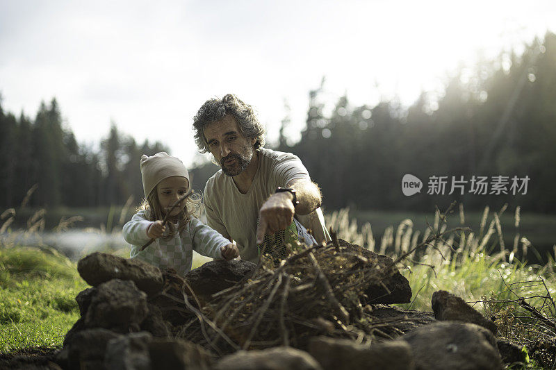 爸爸和孩子准备营火。一家人在湖边露营。本空间