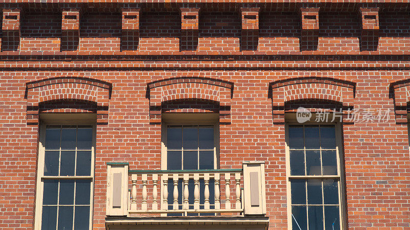 古老的红砖建筑，有扁平的玻璃窗和木阳台
