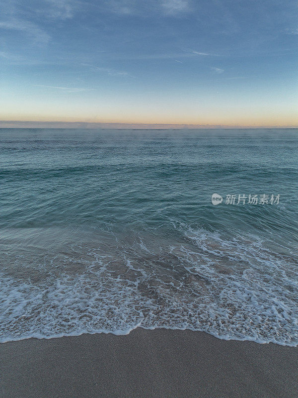 海滩岸边的波浪背景与日出在地平线上
