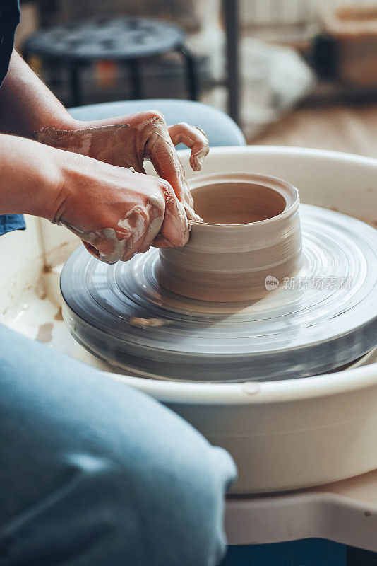 陶工的女性双手在车轮上塑造粘土制品