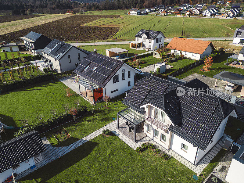 低空近景新密集农村住宅开发，大多是灰色屋顶，一些绿色景观，小树。有平屋顶的现代住宅