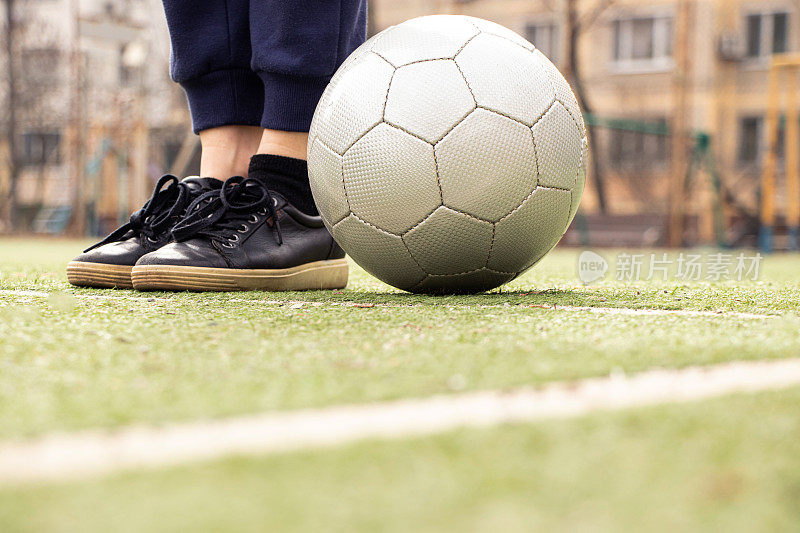 乌克兰，足球场上的女性腿和一个灰色的足球，在院子里踢足球
