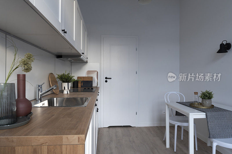 厨房作为家庭展示室内，配有舒适设计的木制厨房台面和厨房用具。用水龙头洗水槽。