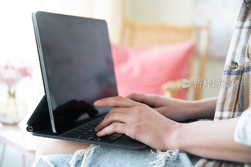 年轻女子坐在家里的沙发上，用着黑屏的笔记本电脑。