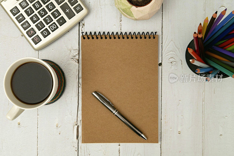 顶视图木制办公桌与咖啡杯，仙人掌壶，彩色铅笔，计算器和空白笔记本