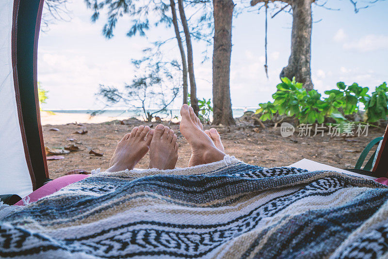 从海滩上露营的帐篷里看到的一对夫妇的脚